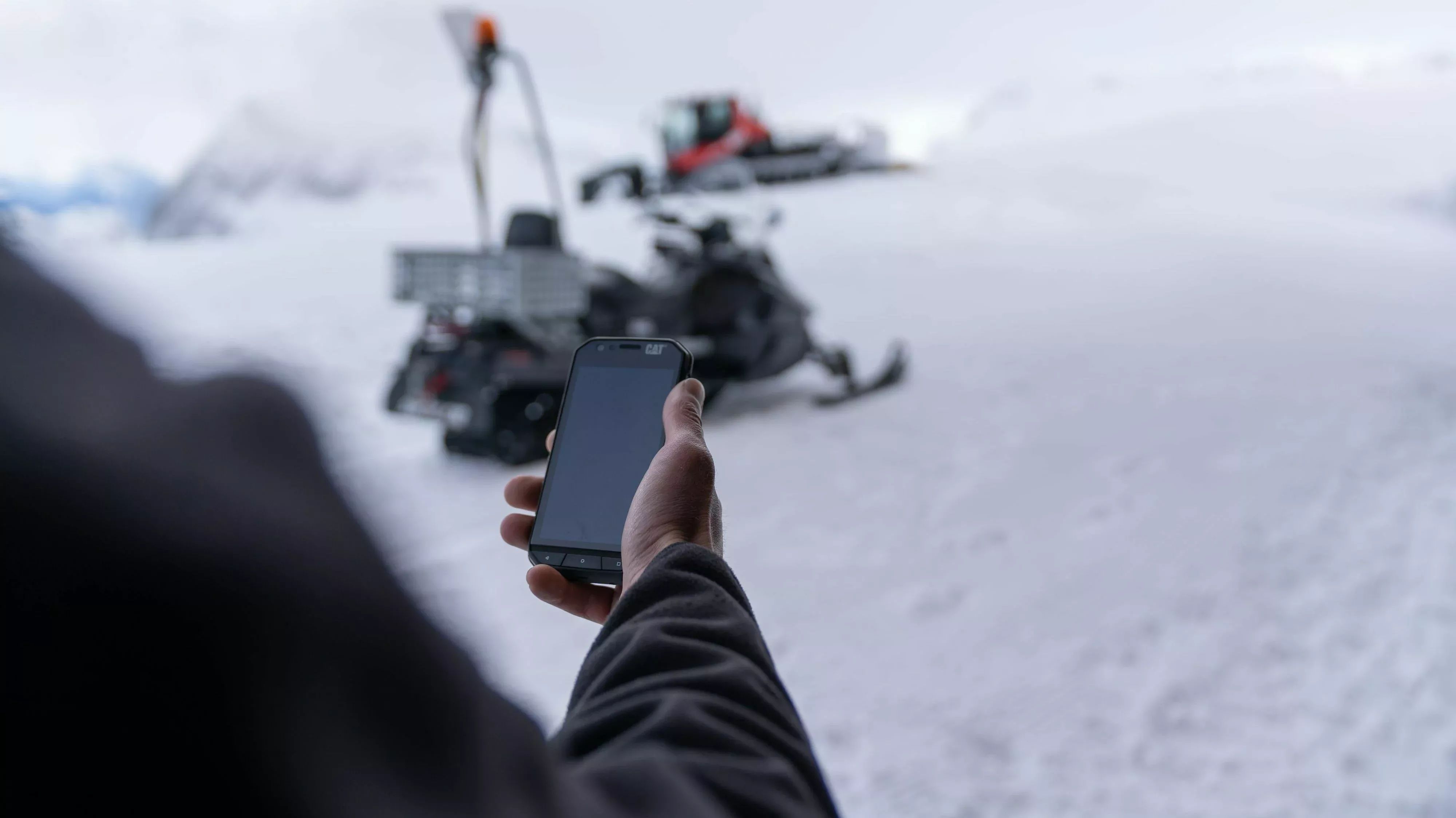 Mitarbeiter im Skigebiet mit Handy in der Hand