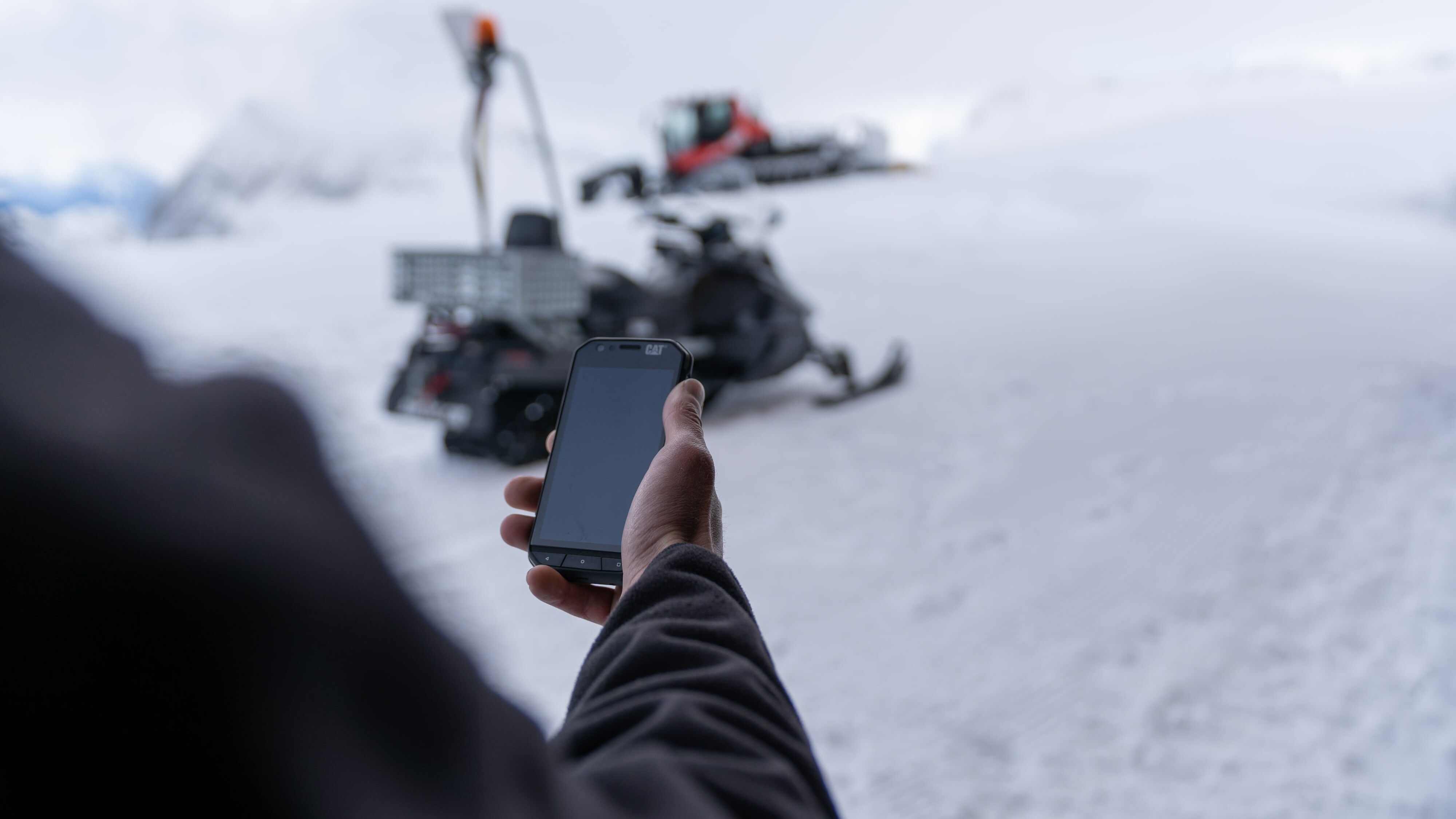 Mitarbeiter im Skigebiet mit Handy in der Hand