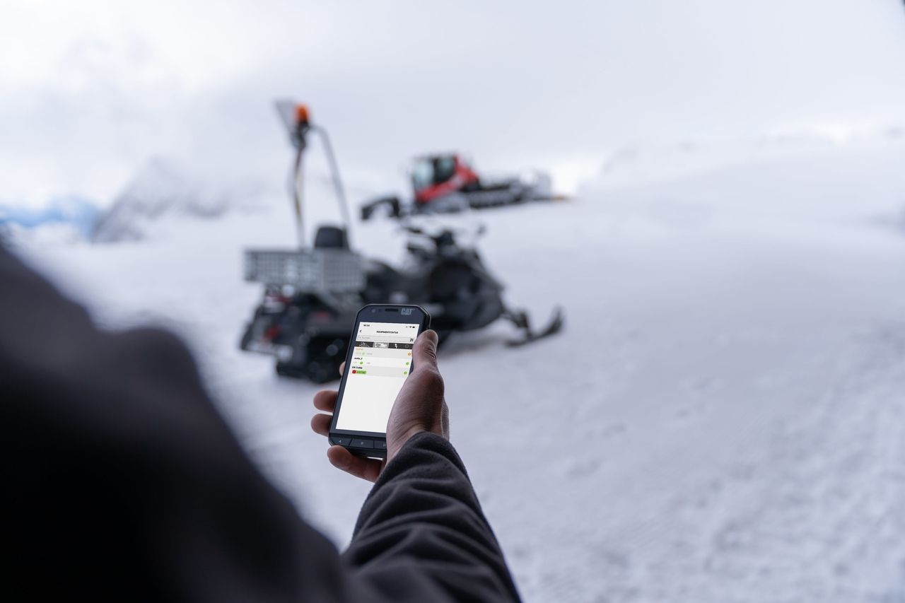 SNOWsat sur le téléphone portable, avec PistenBully en arrière-plan