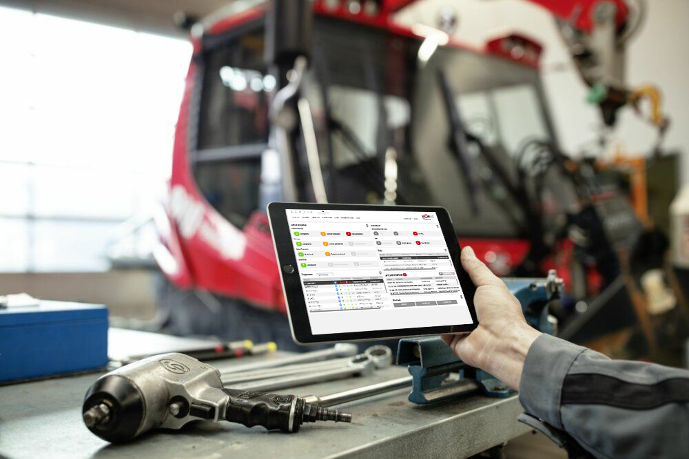 App SNOWsat sul tablet, un PistenBully sullo sfondo