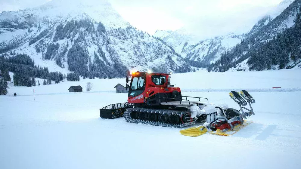 PistenBully räumt Schnee mit Schild