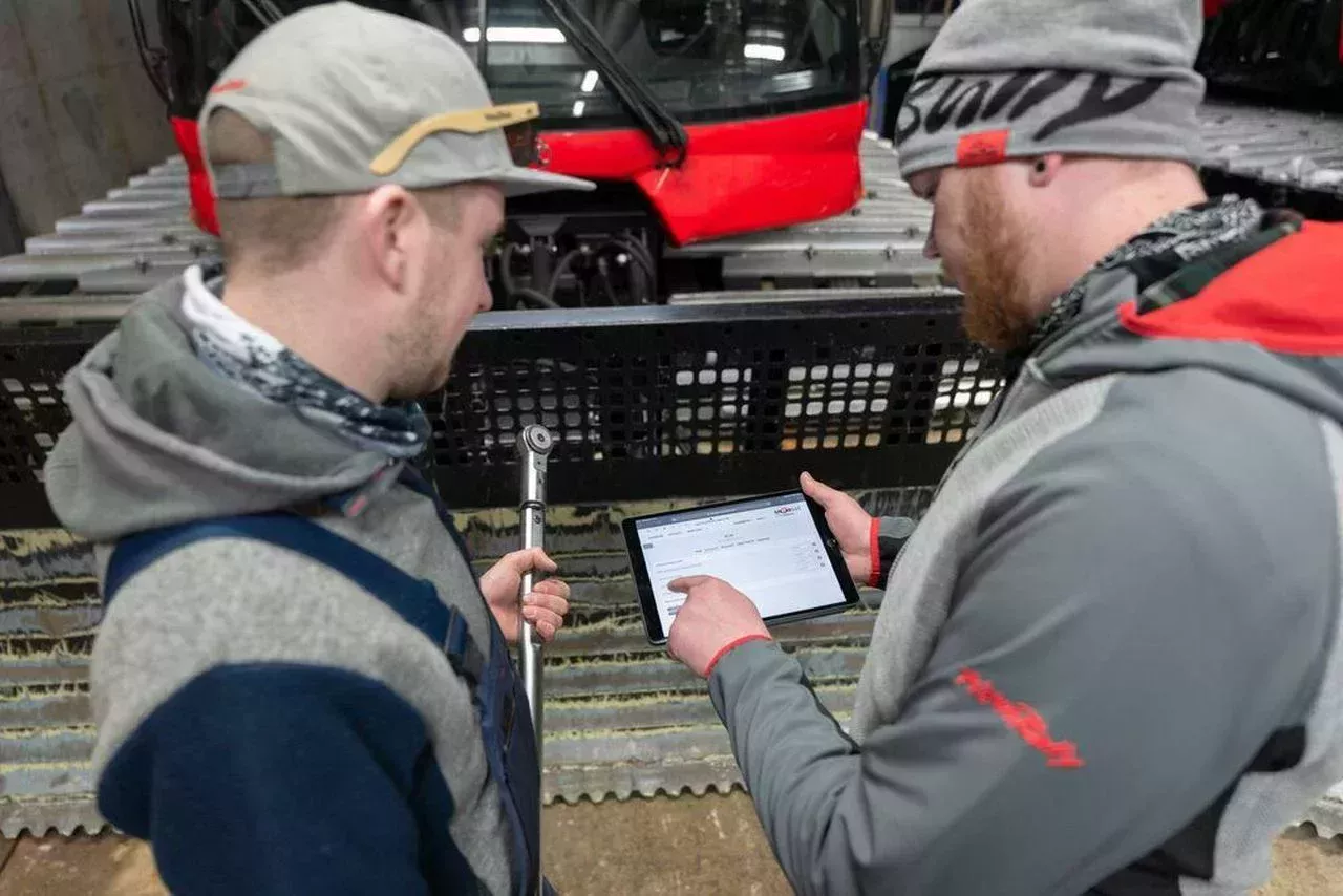 SNOWsat App auf dem Tablet, im Hintergrund ein PistenBully