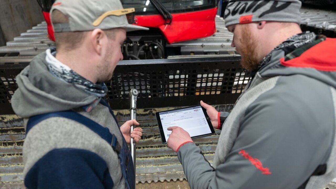 SNOWsat sur la tablette, avec un PistenBully en arrière-plan